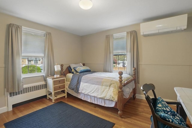 bedroom featuring radiator heating unit, multiple windows, a wall mounted AC, and wood finished floors