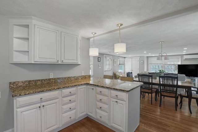 kitchen with white cabinetry, a wall mounted AC, dark wood finished floors, and dark stone countertops