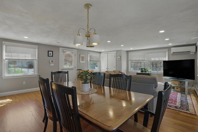 dining space with a wall unit AC, wood finished floors, baseboards, a chandelier, and recessed lighting