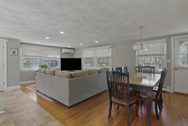 living area featuring an inviting chandelier, a wall mounted air conditioner, recessed lighting, baseboards, and wood finished floors
