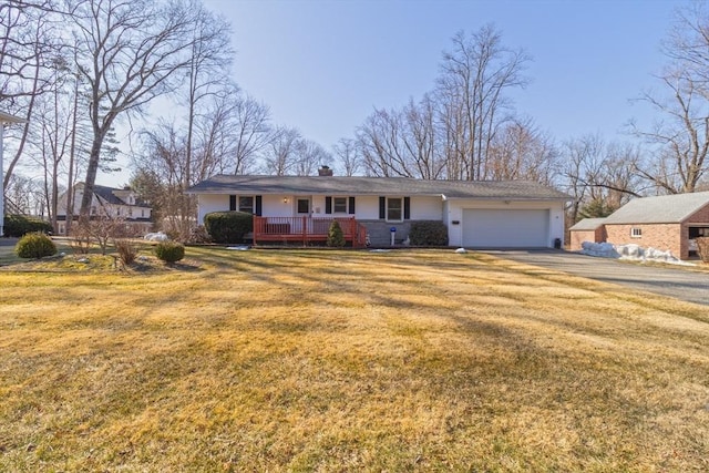 ranch-style home featuring driveway, an attached garage, a chimney, and a front lawn