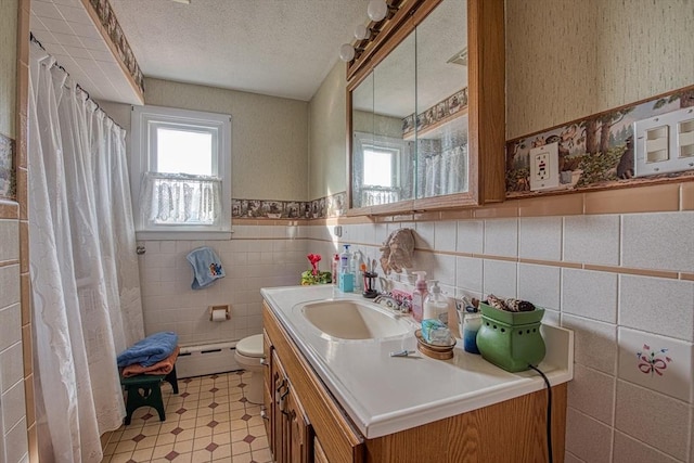 bathroom with vanity, a baseboard heating unit, toilet, a textured ceiling, and tile walls