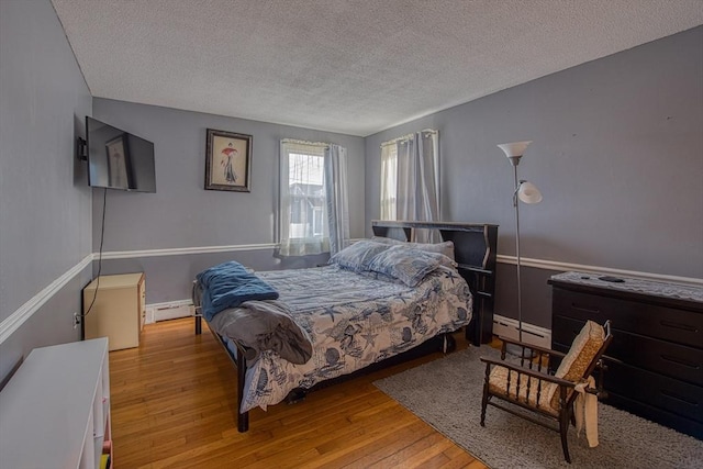 bedroom with a textured ceiling, light hardwood / wood-style floors, and baseboard heating