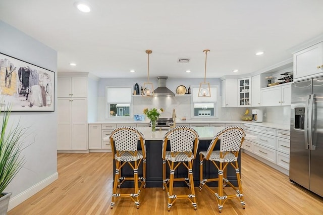 31 Orchard Rd, Hamilton, MA 01982 - kitchen with stainless steel fridge, light countertops, wall chimney range hood, light wood-type flooring, and white cabinetry