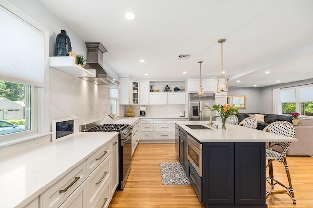 31 Orchard Rd, Hamilton, MA 01982 - kitchen with appliances with stainless steel finishes, range hood, white cabinets, a kitchen bar, and light countertops