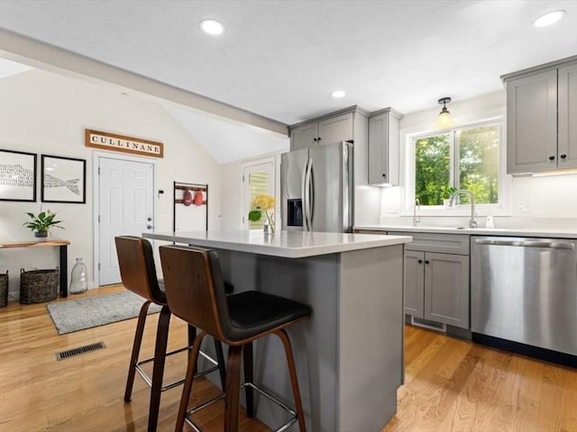 17 Clifton Ave, Scituate, MA 02066 - kitchen with appliances with stainless steel finishes, gray cabinets, lofted ceiling, a kitchen breakfast bar, and light wood-style floors