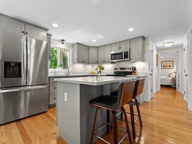 17 Clifton Ave, Scituate, MA 02066 - kitchen with appliances with stainless steel finishes, gray cabinets, light countertops, a kitchen bar, and light wood-style flooring