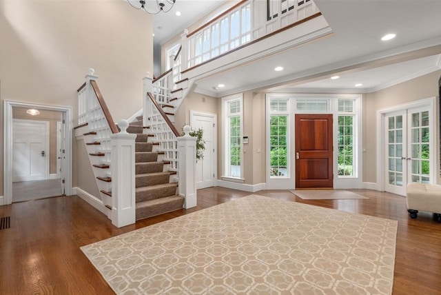 entryway featuring crown molding, baseboards, stairway, wood finished floors, and a towering ceiling