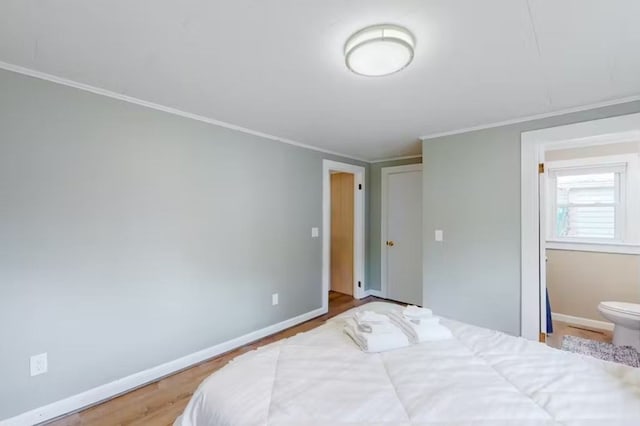 bedroom featuring crown molding, hardwood / wood-style flooring, and connected bathroom