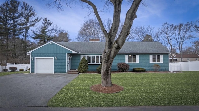 ranch-style house with an attached garage, roof with shingles, a front lawn, and fence