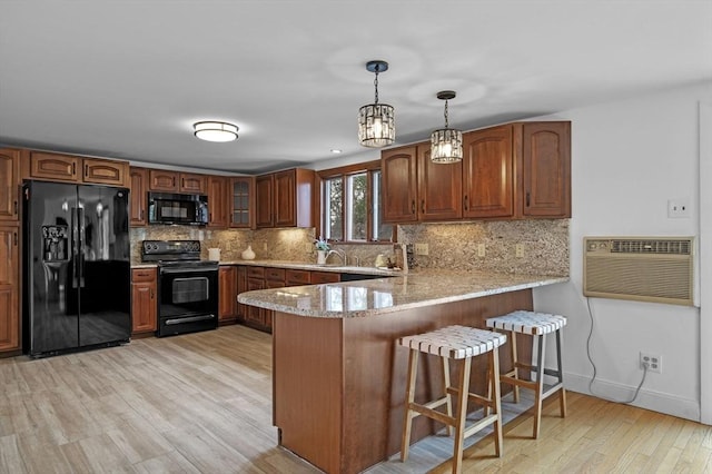 kitchen featuring backsplash, light wood-style flooring, a peninsula, and black appliances