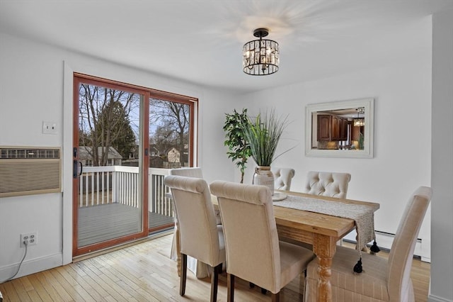 dining room with a wall mounted air conditioner, light wood-style floors, a baseboard radiator, baseboards, and a chandelier