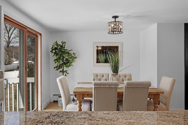 dining area featuring a baseboard heating unit, baseboards, a notable chandelier, and wood finished floors