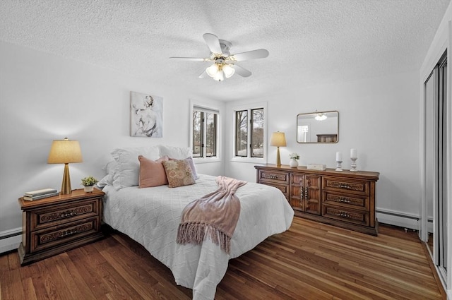 bedroom featuring wood finished floors, ceiling fan, a closet, a textured ceiling, and a baseboard heating unit