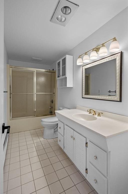 full bathroom featuring combined bath / shower with glass door, toilet, vanity, and tile patterned floors