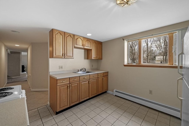 kitchen with a sink, a baseboard heating unit, light countertops, light tile patterned floors, and range