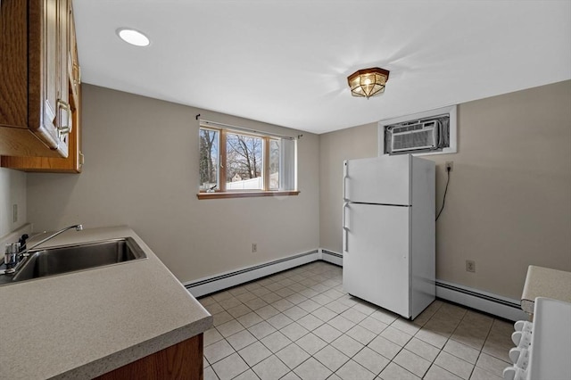 kitchen with light countertops, baseboard heating, freestanding refrigerator, a wall mounted AC, and a sink