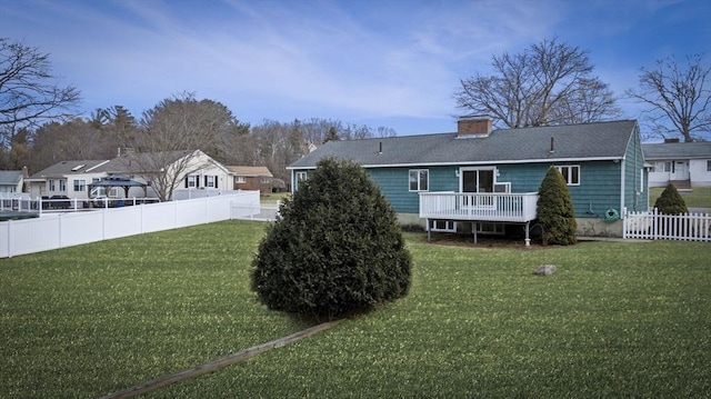 rear view of house featuring a lawn, a deck, a chimney, and fence