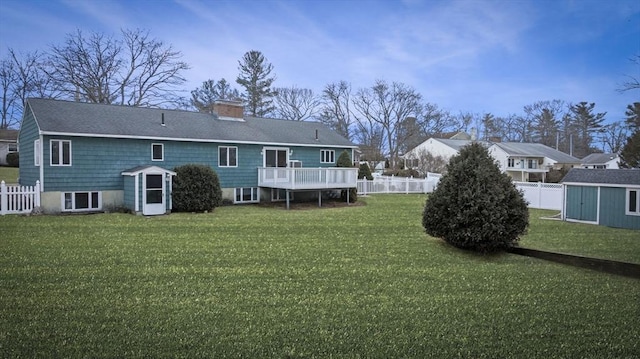 back of house featuring an outbuilding, a lawn, a chimney, and a fenced backyard