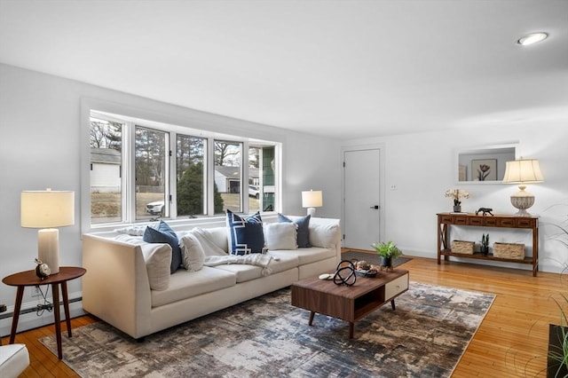 living area with baseboards, wood-type flooring, and a baseboard heating unit