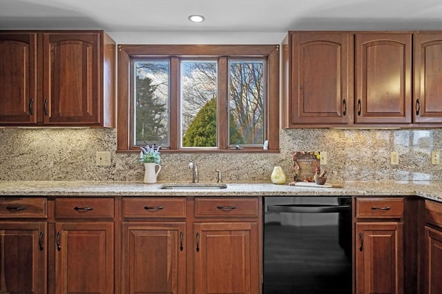 kitchen with a sink, backsplash, light stone counters, and black dishwasher