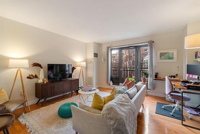 living room featuring light wood-type flooring, a desk, and baseboards