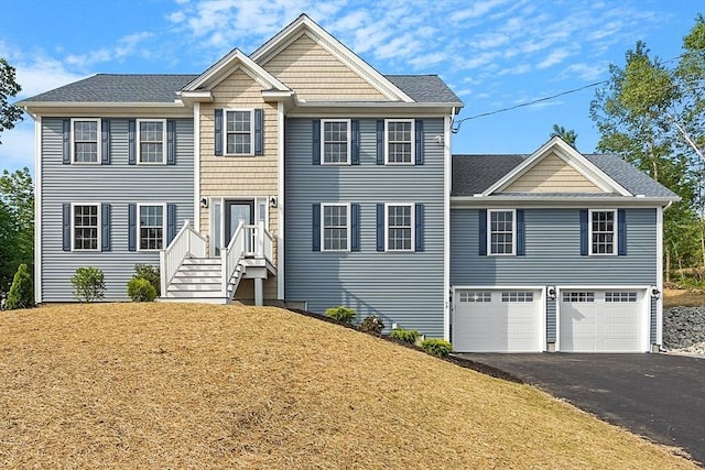 colonial house with an attached garage, aphalt driveway, roof with shingles, and a front yard