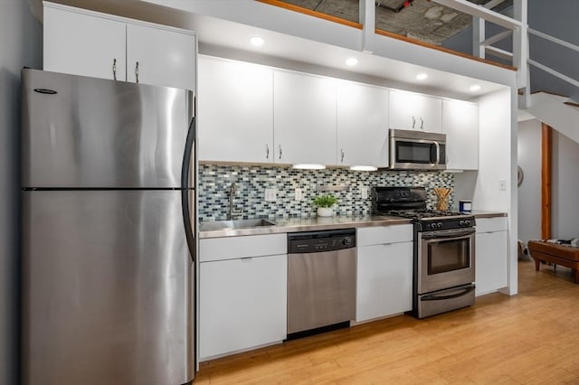 kitchen featuring white cabinets, appliances with stainless steel finishes, light hardwood / wood-style flooring, and sink