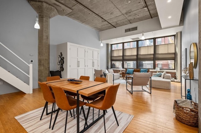 dining area with a high ceiling and light hardwood / wood-style flooring