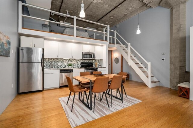 dining area with a high ceiling and light wood-type flooring