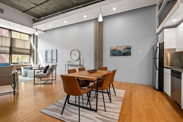 dining room with a high ceiling and light wood-type flooring