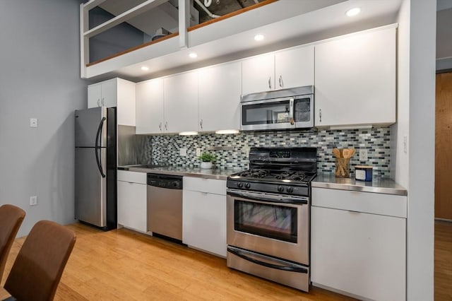 kitchen featuring white cabinets, appliances with stainless steel finishes, backsplash, and stainless steel counters