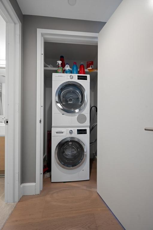 100 Lovejoy Wharf Unit 6J, Boston, MA 02114 - laundry area featuring stacked washer / drying machine and wood finished floors