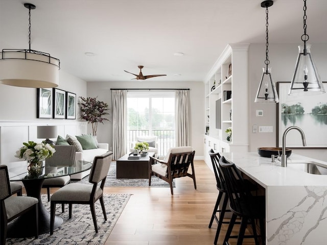 interior space featuring light stone counters, sink, pendant lighting, and light hardwood / wood-style floors