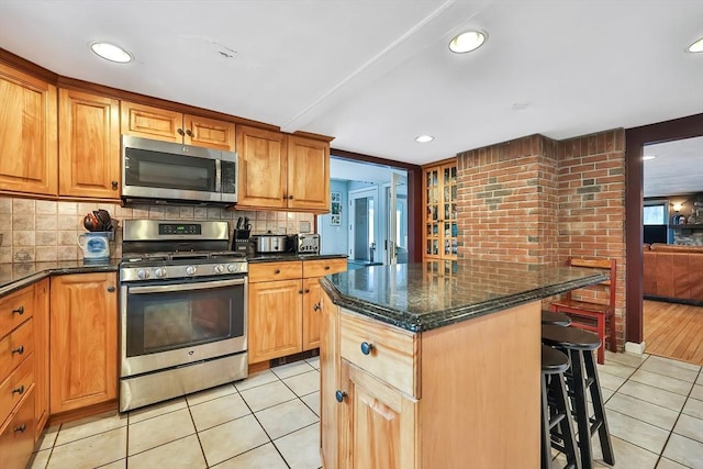 371-377 Franklin St, Wrentham, MA 02093 - kitchen with stainless steel appliances, light tile patterned floors, a kitchen bar, backsplash, and recessed lighting