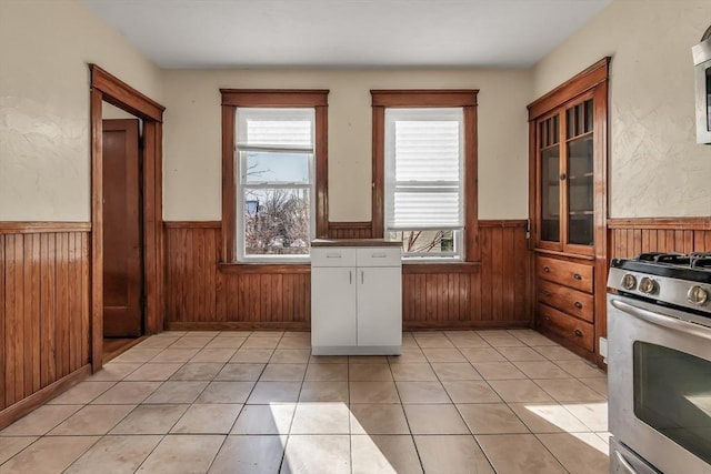 kitchen with light tile patterned floors, gas range, and wooden walls