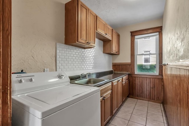 laundry area with sink, light tile patterned floors, wooden walls, cabinets, and washer / clothes dryer