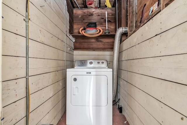 clothes washing area featuring washer / dryer and wood walls