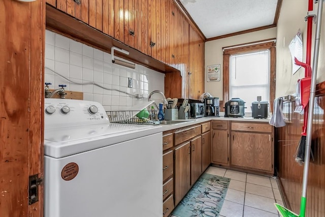 washroom featuring crown molding, washer / dryer, sink, and light tile patterned floors