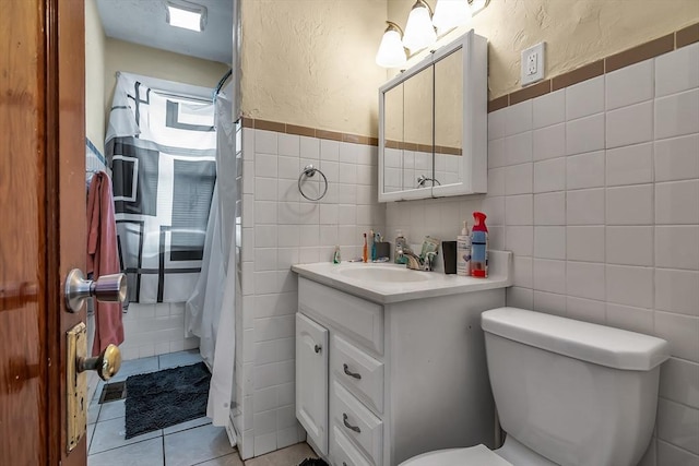 bathroom featuring tile patterned floors, vanity, toilet, and tile walls