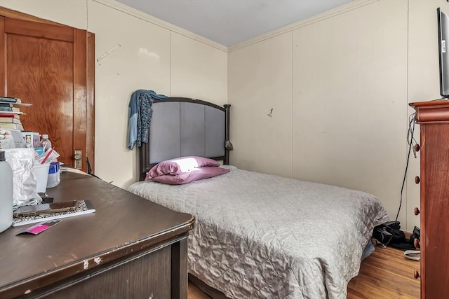 bedroom with ornamental molding and light wood-type flooring