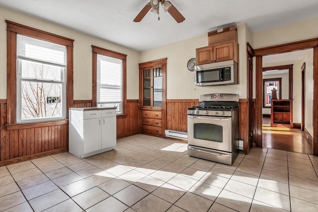 kitchen with appliances with stainless steel finishes, wooden walls, and light tile patterned floors