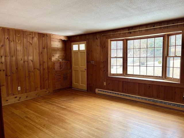 entryway with wooden walls, light wood-type flooring, a textured ceiling, and baseboard heating