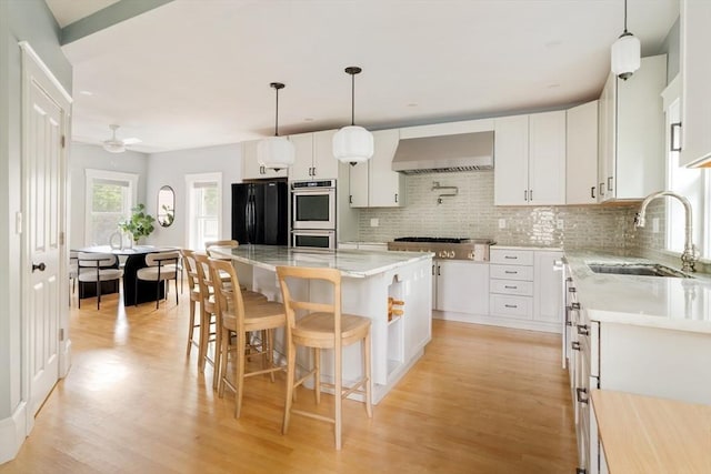 15 Berkeley St, Somerville, MA 02143 - kitchen featuring appliances with stainless steel finishes, wall chimney range hood, light wood finished floors, and tasteful backsplash