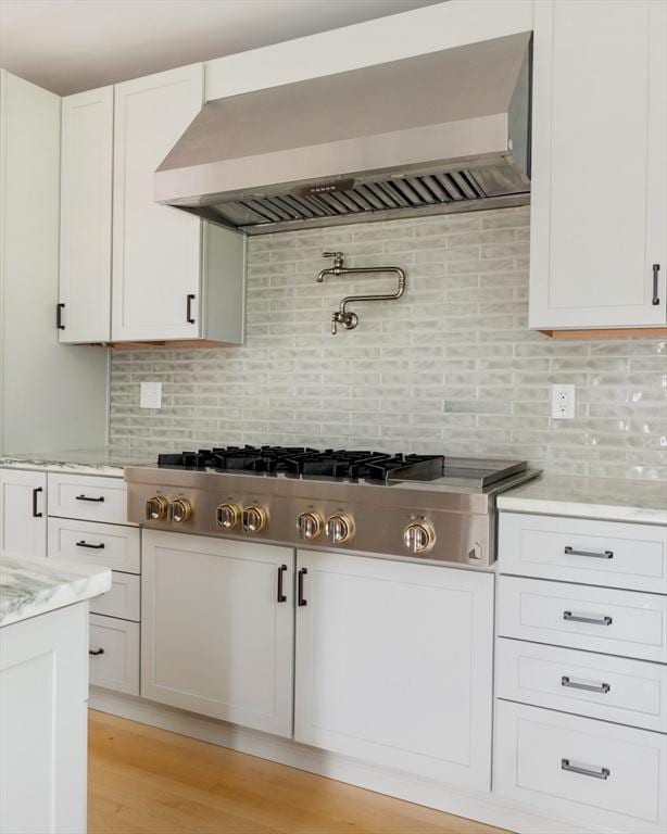 15 Berkeley St, Somerville, MA 02143 - kitchen with wall chimney exhaust hood, stainless steel gas stovetop, white cabinetry, tasteful backsplash, and light wood finished floors