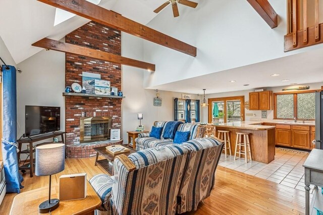 22 Woodside Dr, Falmouth, MA 02536 - living room with high vaulted ceiling, a ceiling fan, light wood finished floors, beam ceiling, and a fireplace