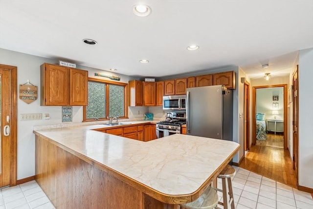 22 Woodside Dr, Falmouth, MA 02536 - kitchen with appliances with stainless steel finishes, light countertops, a peninsula, light tile patterned flooring, and recessed lighting