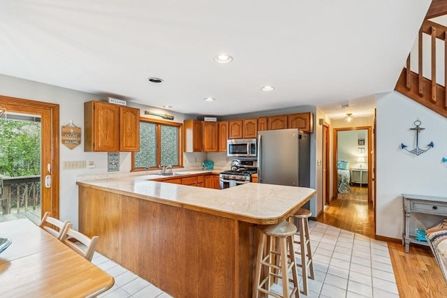 22 Woodside Dr, Falmouth, MA 02536 - kitchen featuring appliances with stainless steel finishes, a sink, a peninsula, light countertops, and brown cabinets
