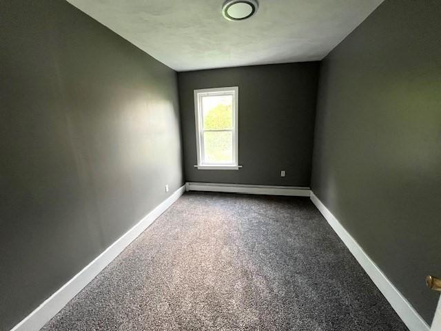 14 Felton St, Fitchburg, MA 01420 - empty room featuring a baseboard radiator and dark carpet