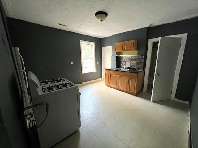 14 Felton St, Fitchburg, MA 01420 - kitchen with white gas range oven, brown cabinets, light flooring, tasteful backsplash, and dark countertops